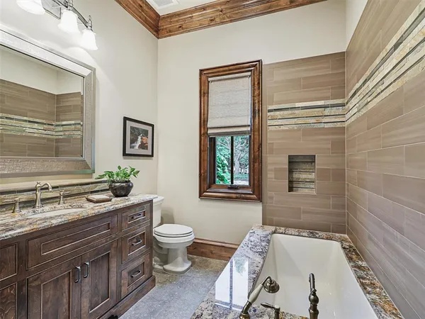 a bathroom with a granite countertop sink a toilet a mirror and shower