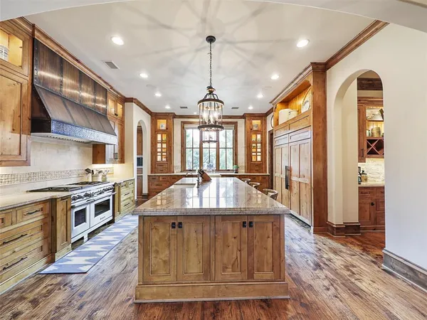 a large kitchen with stainless steel appliances granite countertop a stove a sink dishwasher and a wooden cabinets with wooden floor