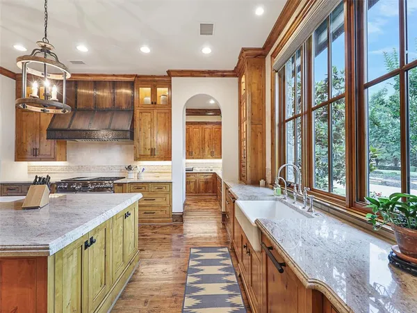 a kitchen with stainless steel appliances granite countertop a sink a stove and a wooden floors