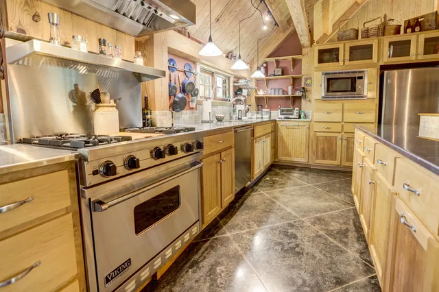 a white kitchen with stainless steel appliances granite countertop a stove and a sink