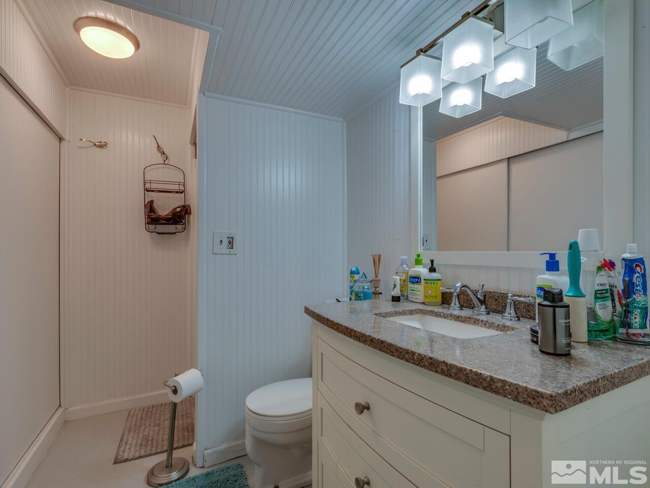1061 Whitaker Drive Reno, NV 89503 - Photo 19 of 20 a bathroom with a granite countertop sink a toilet and a mirror