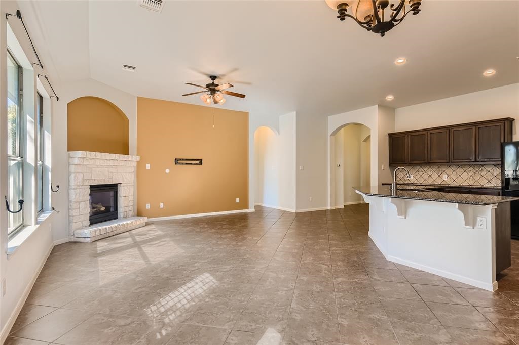 290 Maeves Way Austin, TX 78737 - Photo 3 of 13 An inviting open-concept living area boasts a stone fireplace, high ceilings, and a kitchen island with granite countertops.