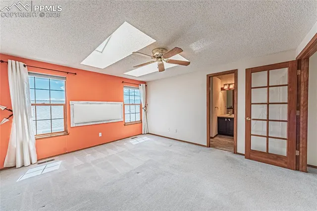 an empty room with windows and ceiling fan