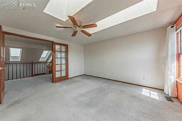 an empty room with windows and fan