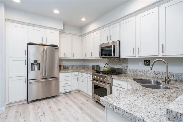 a kitchen with stainless steel appliances granite countertop a refrigerator stove top oven and sink