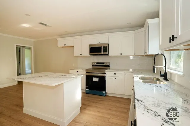 a kitchen with granite countertop a stove top oven sink and cabinets