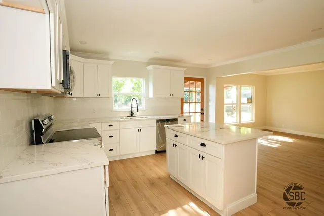 a kitchen that has a lot of white cabinets and wooden floor