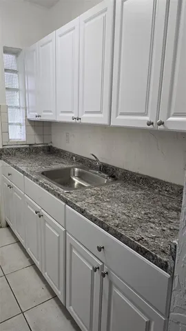 a kitchen with granite countertop white cabinets and sink