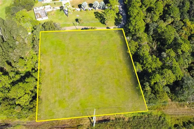 an aerial view of residential houses with outdoor space and trees