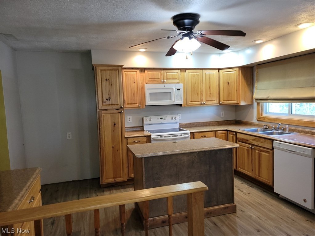 22922 Putney Ridge Road Quaker City, OH 43773 - Photo 12 of 31 Kitchen featuring range, brown cabinets, light countertops, light hardwood floors, white dishwasher, and ceiling fan