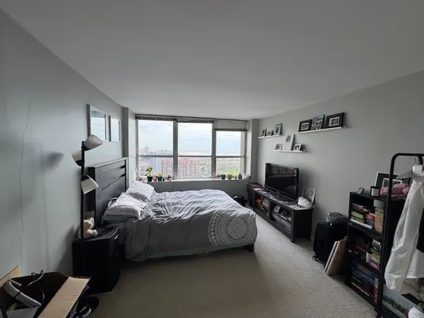 a bedroom with a bed a couch and a flat tv screen on the dresser