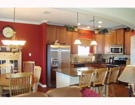 a kitchen with granite countertop a refrigerator a stove top oven a sink dishwasher and dining table with wooden floor