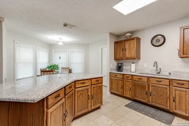 a large kitchen with kitchen island granite countertop a sink and white cabinets with wooden floor