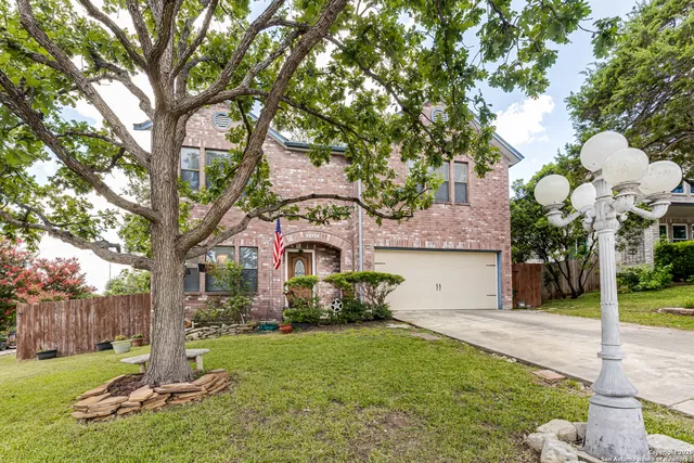 a front view of a house with a yard and tree