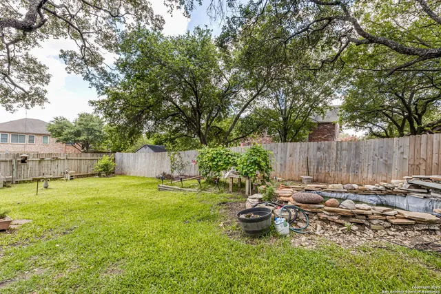 a backyard of a house with table and chairs and wooden fence