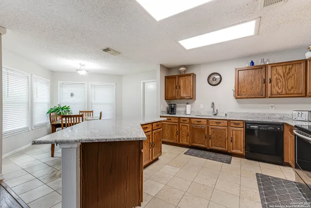 a kitchen with granite countertop a sink a stove top oven a counter space and cabinets