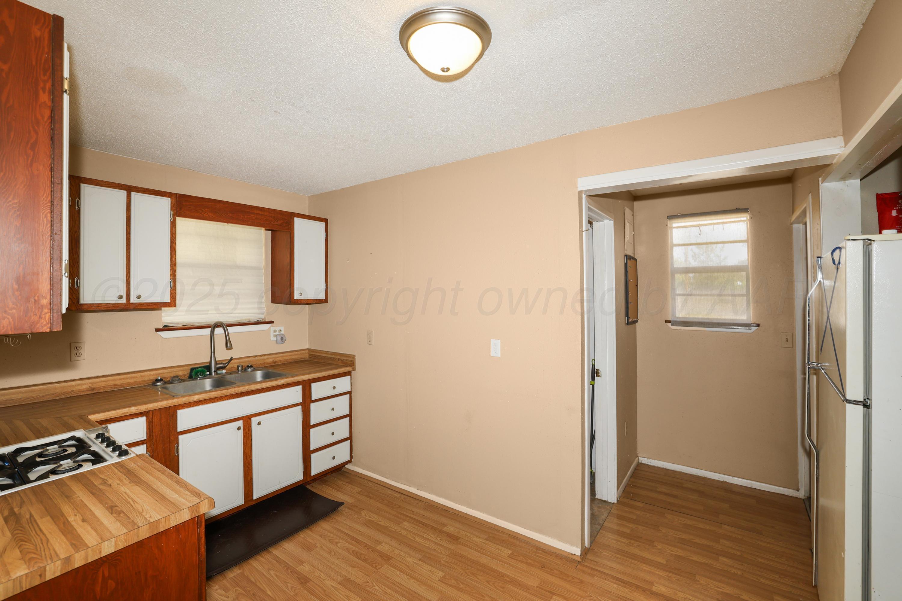 7682 Back Acres Road Amarillo, TX 79119 - Photo 22 of 27 a kitchen with sink cabinets and wooden floor