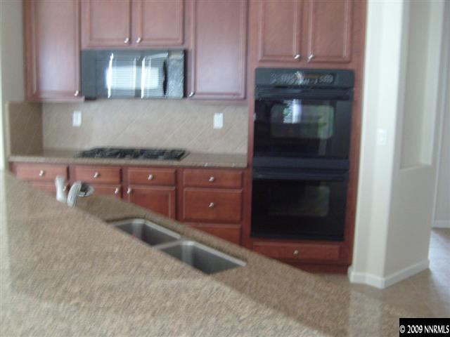 10075 Bull Rider Court Reno, NV 89521 - Photo 4 of 9 a kitchen with granite countertop a refrigerator and a stove