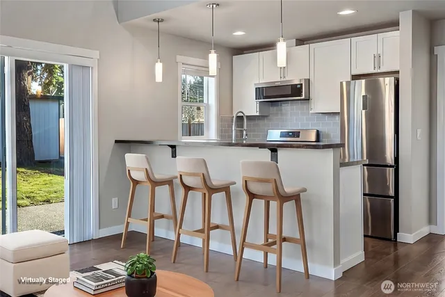 a kitchen with stainless steel appliances a dining table chairs refrigerator and microwave