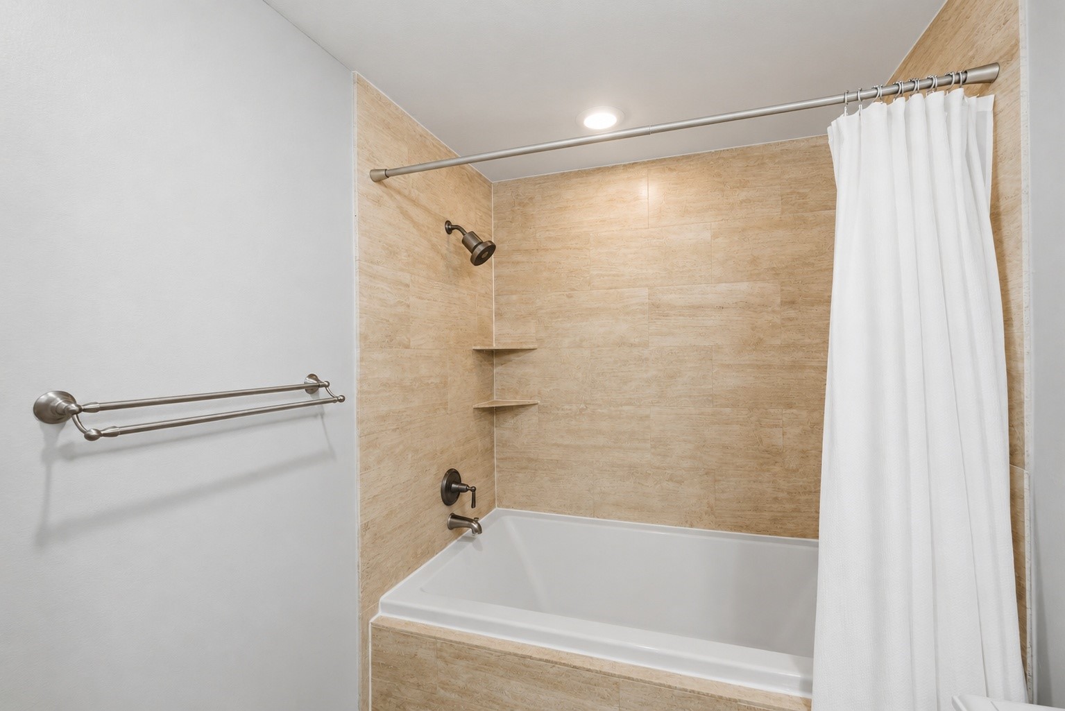 4733 Carleen Road Houston, TX 77092 - Photo 14 of 22 Floor-to-ceiling travertine tile surrounds the tub and shower, giving the primary bath a timeless, spa-inspired finish.