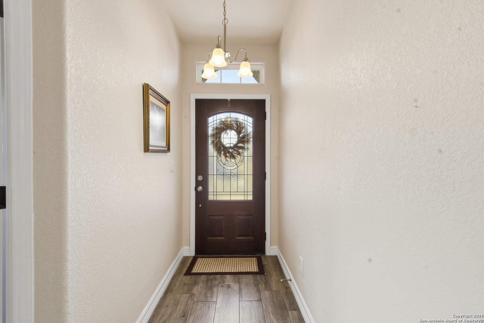 101 Sutton Place Uvalde, TX 78801 - Photo 9 of 36 a view of a hallway with wooden floor and a chandelier
