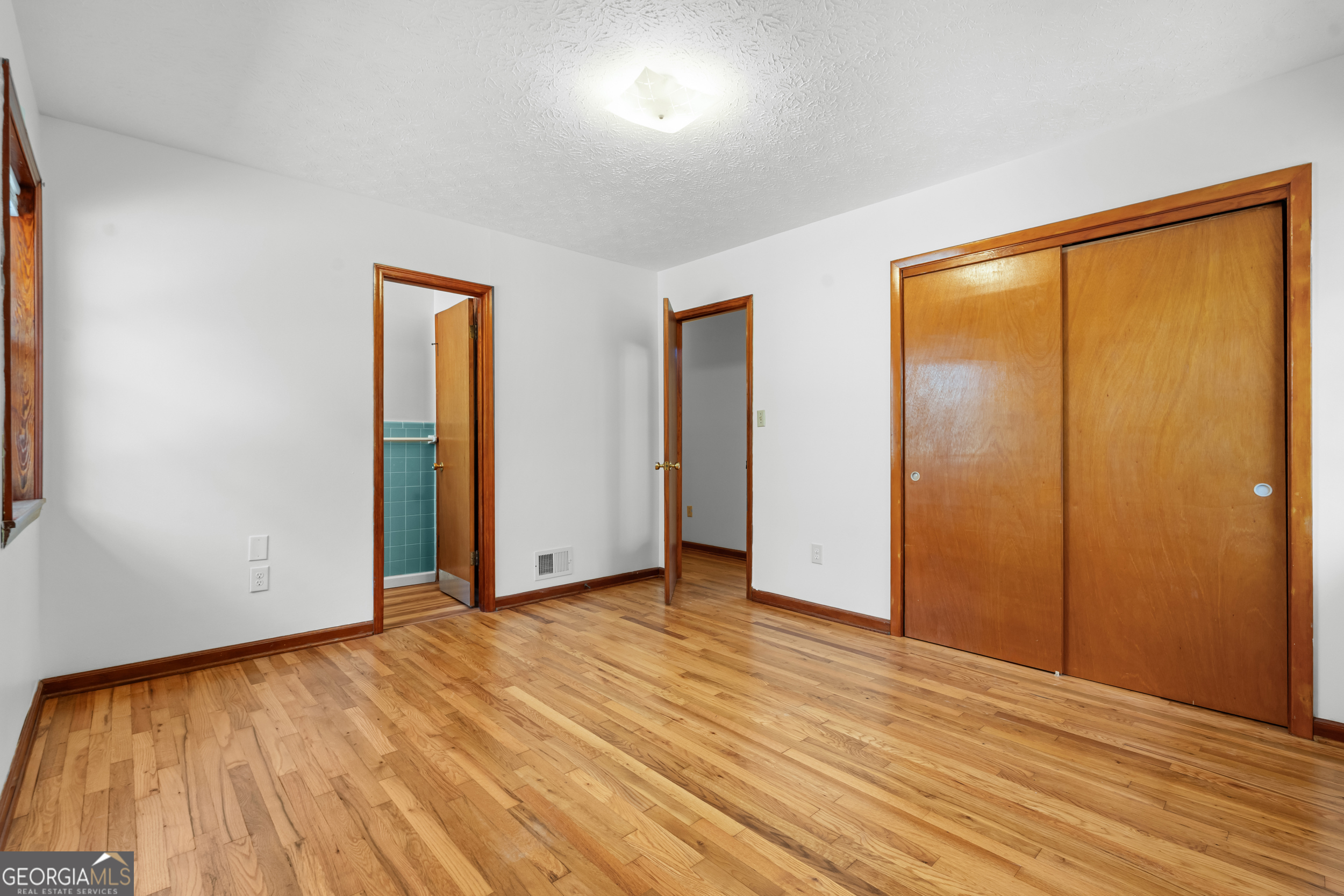 181 Heidt Road Guyton, GA 31312 - Photo 11 of 24 a view of an empty room with wooden floor and a window