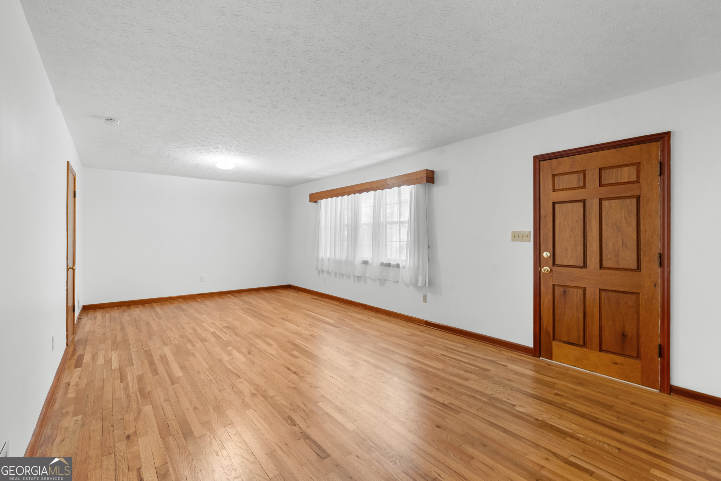181 Heidt Road Guyton, GA 31312 - Photo 4 of 24 an empty room with wooden floor and windows