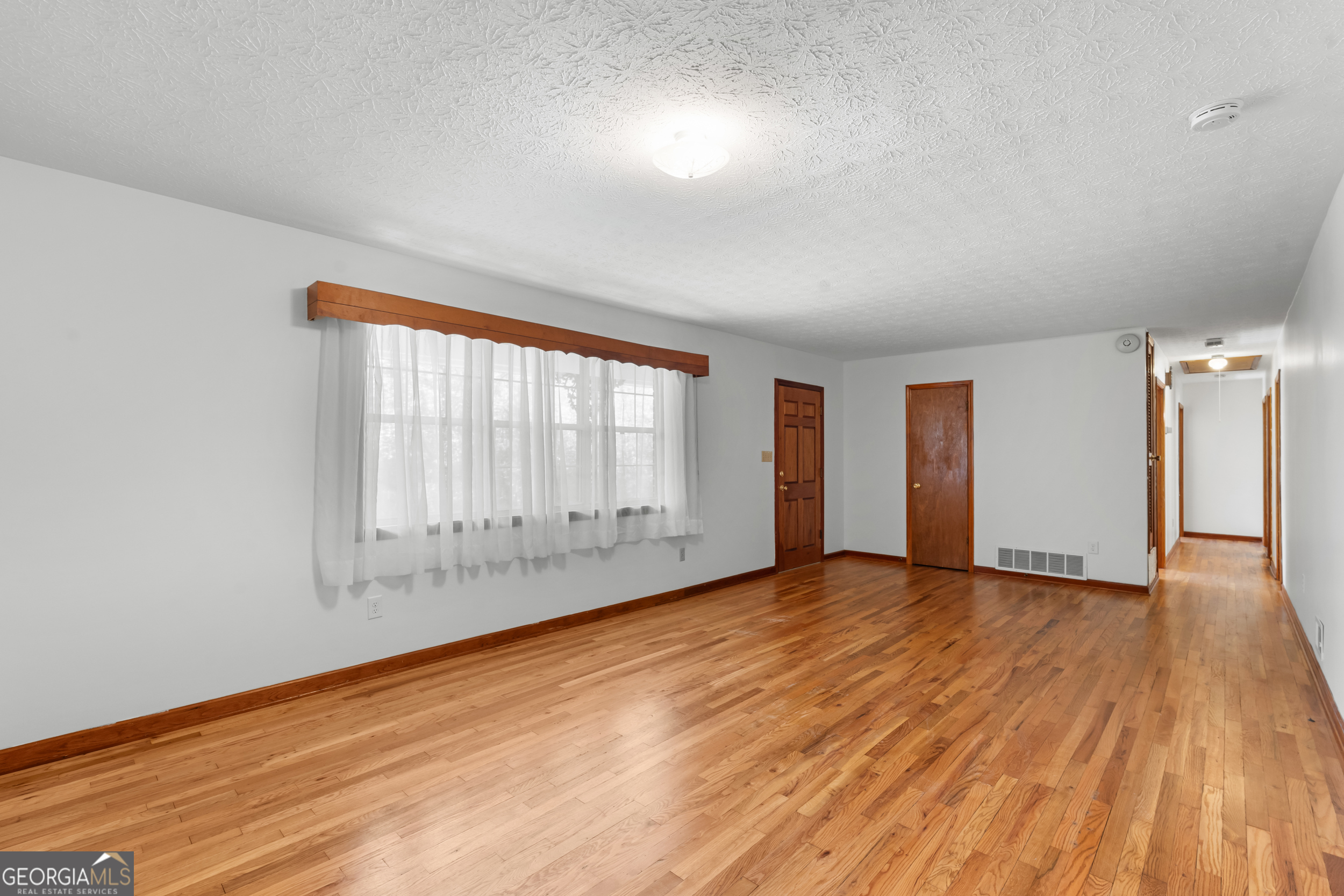 181 Heidt Road Guyton, GA 31312 - Photo 5 of 24 a view of an empty room with wooden floor and a window