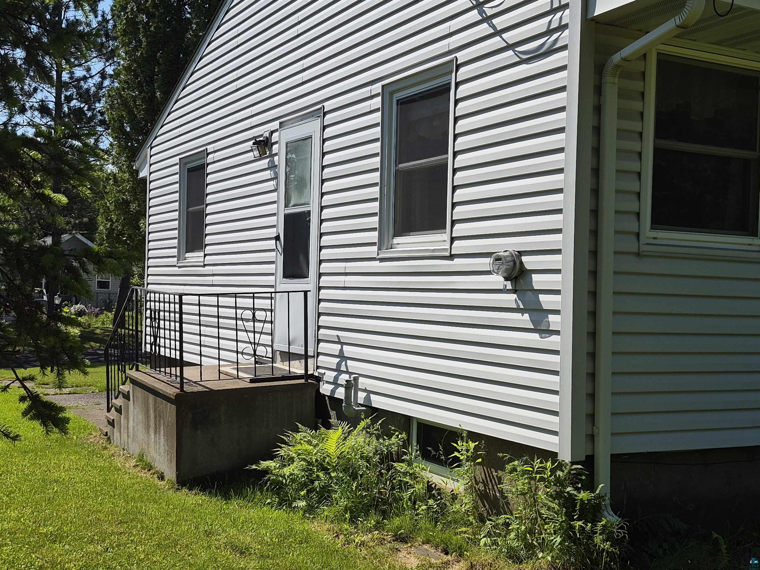 2109 West 22nd Street Duluth, MN 55811 - Photo 2 of 29 White vinyl siding exterior with multiple windows and a side entry door