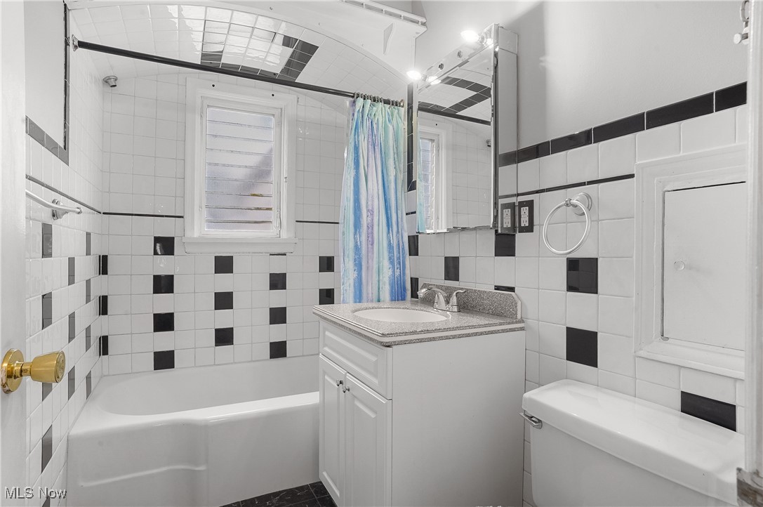 3206 9th Street Northwest Canton, OH 44708 - Photo 16 of 32 Full bathroom with vanity, shower / bathtub combination with curtain, toilet, and tile walls