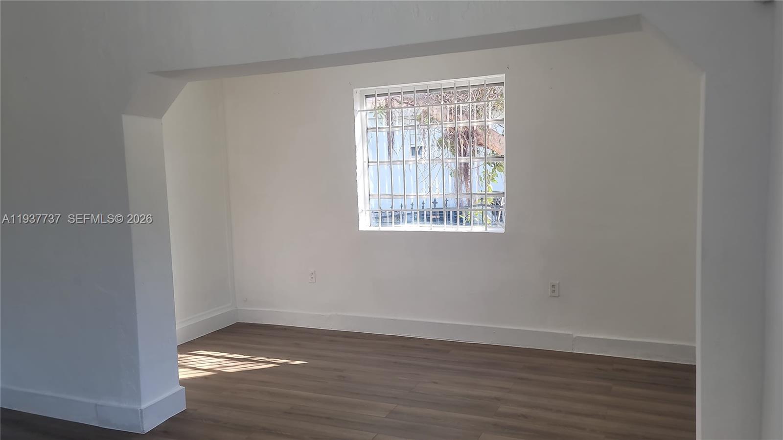 2951 Northwest 49th Street Miami, FL 33142 - Photo 12 of 19 a view of an empty room with wooden floor and a window