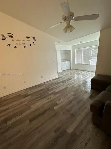 a view of an empty room with a window and a ceiling fan