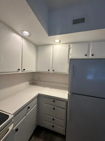 a kitchen with cabinets and a refrigerator