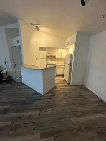 a view of a kitchen with wooden floor and electronic appliances