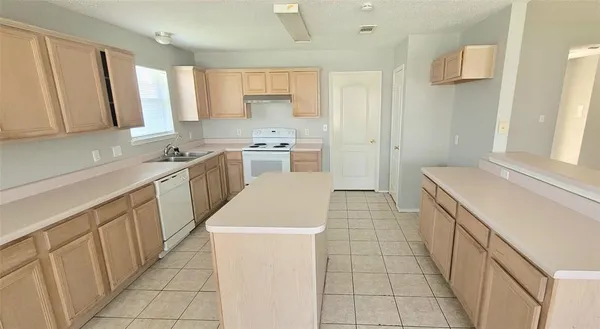 a kitchen with a sink a stove top oven a refrigerator and white cabinets