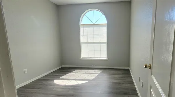 an empty room with wooden floor and window