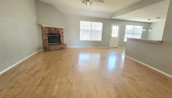 an empty room with windows and fireplace