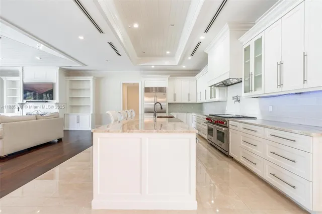 a large kitchen with cabinets chairs and wooden floor