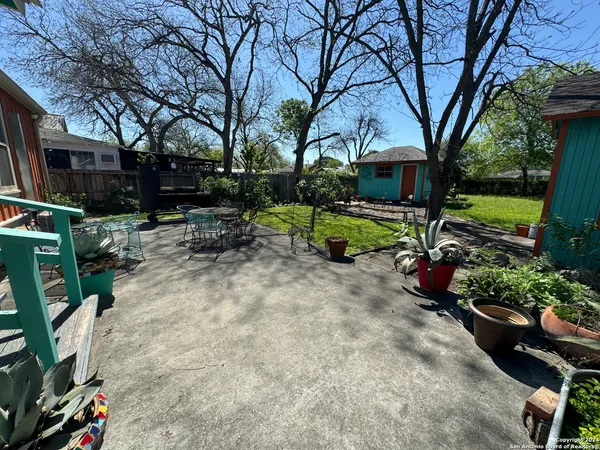 a view of backyard with table and chairs and a large tree