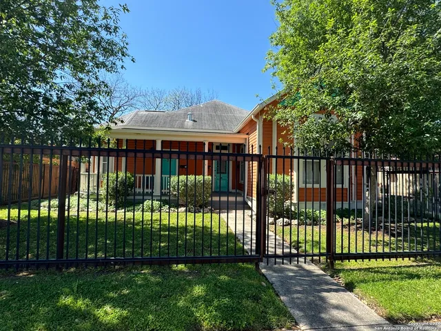 a view of a house in front of a yard with plants and trees