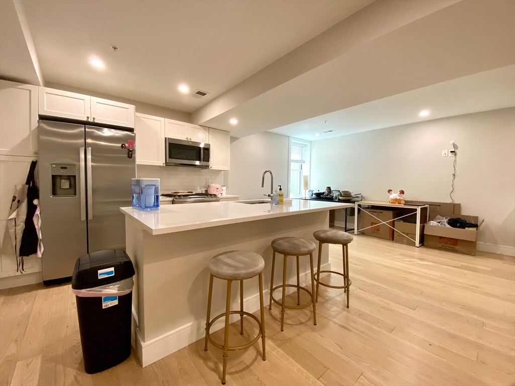 13 Greylock Road, Unit 2 Boston, MA 02134 - Photo 3 of 9 a kitchen with stainless steel appliances kitchen island granite countertop a refrigerator and a stove top oven