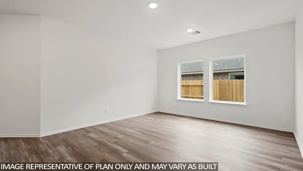 a view of an empty room with wooden floor and windows