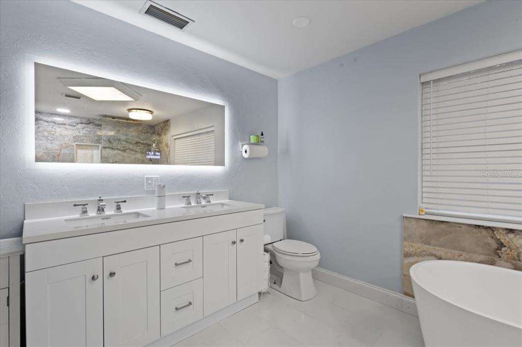 5609 Northwest 53 Court Gainesville, FL 32653 - Photo 22 of 49 a bathroom with a toilet a sink a mirror and a window