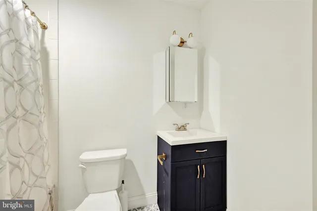 a bathroom with a toilet sink vanity and mirror