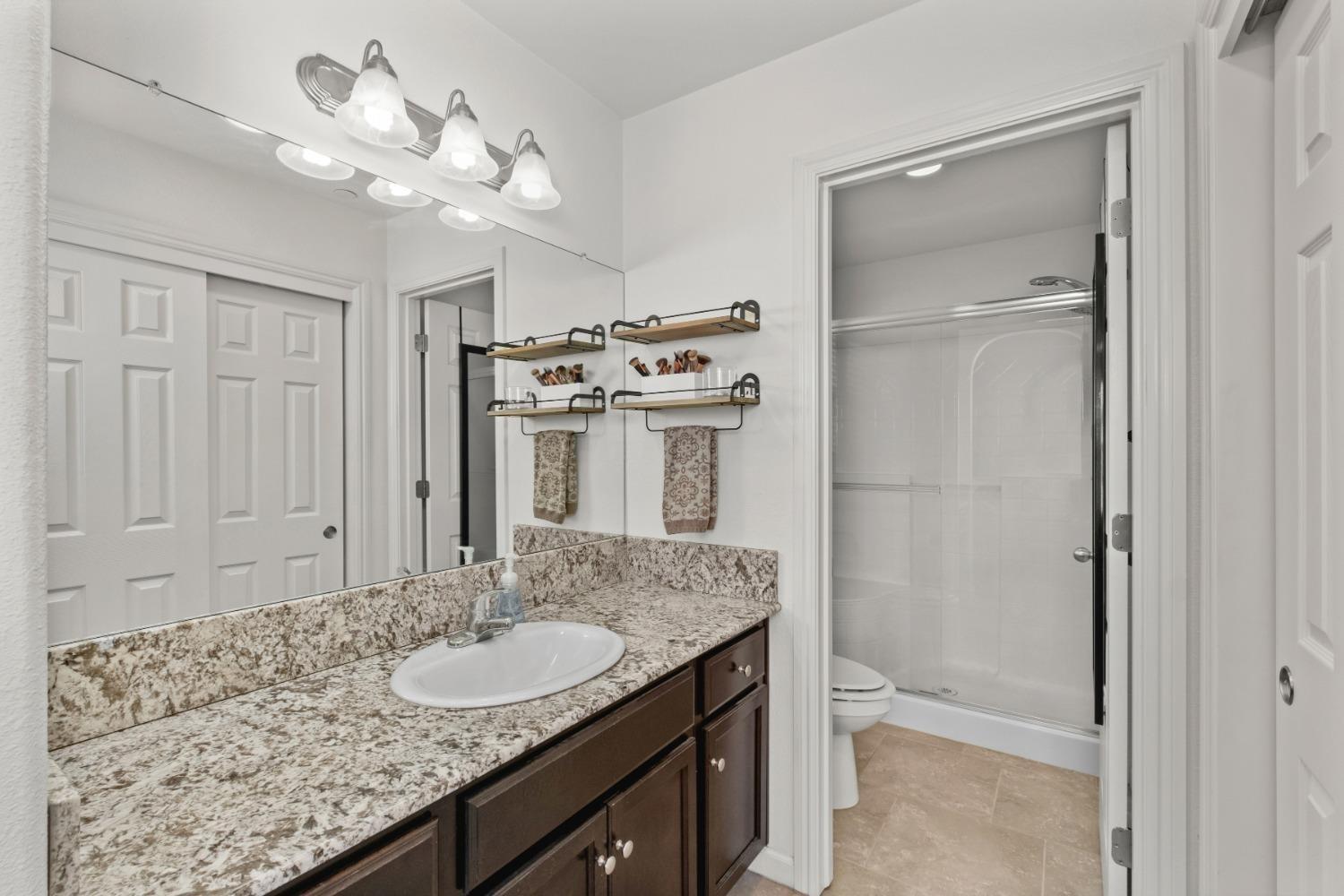 3762 Amity Lane Clovis, CA 93619 - Photo 12 of 15 a bathroom with a granite countertop sink a mirror and a shower