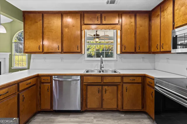 a kitchen with stainless steel appliances a sink a stove a refrigerator cabinets and living room view