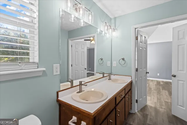 an empty room with wooden floor chandelier fan and windows