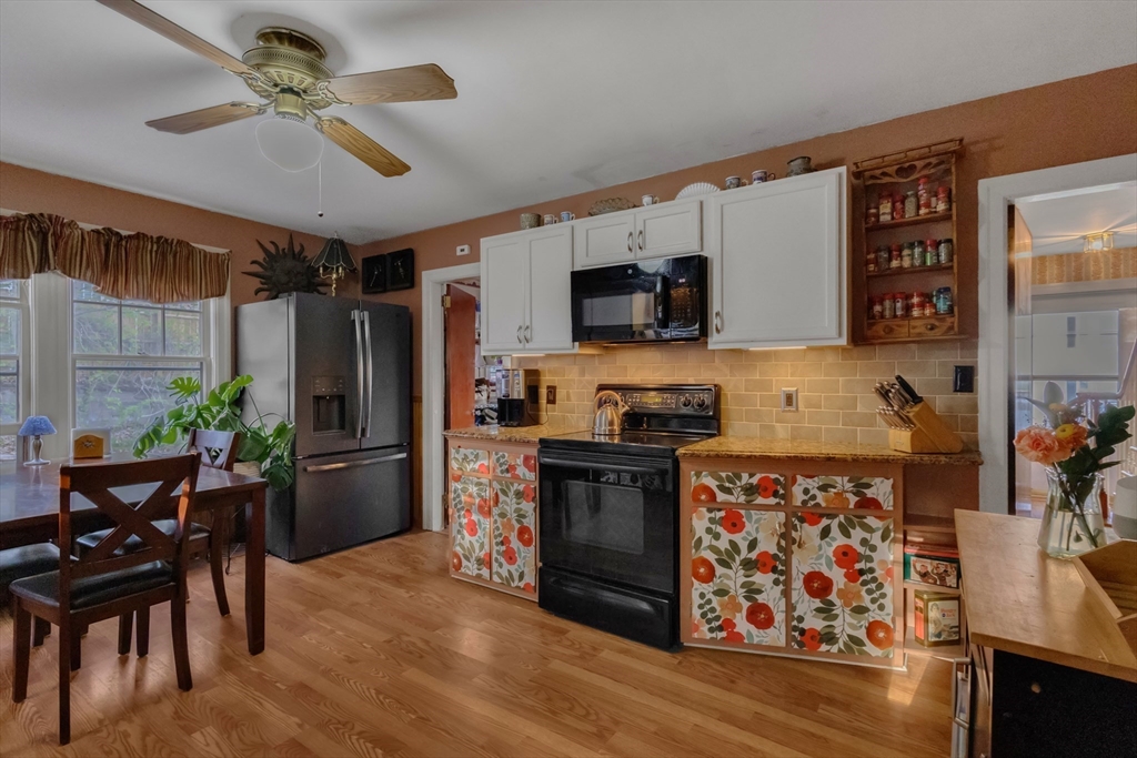 22 Williams Street Dudley, MA 01571 - Photo 13 of 33 a kitchen with stainless steel appliances kitchen island granite countertop a refrigerator a stove top oven a sink dishwasher and a dining table with wooden floor