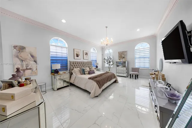 a spacious bedroom with a bed a couch and a flat tv screen on the dresser