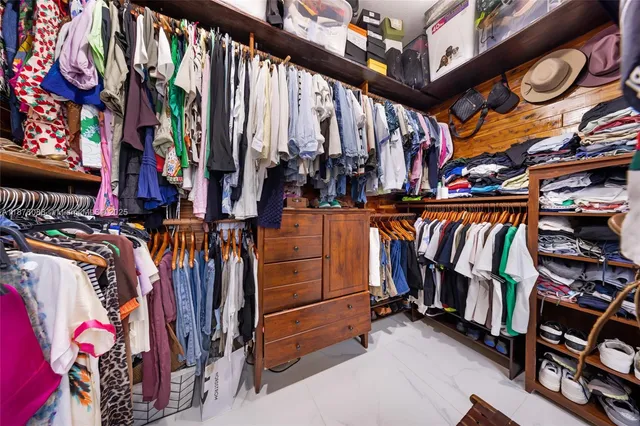 a view of walk in closet with clothes and shoes